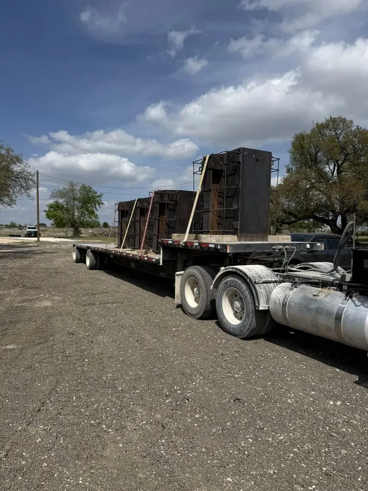 Semi flatbed loaded with steel enclosures under an open sky