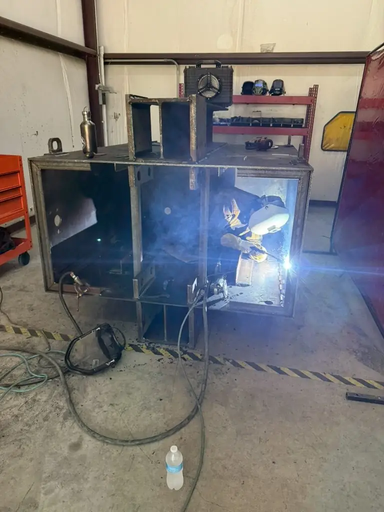 Welder working inside a steel enclosure in the TG Welding bay