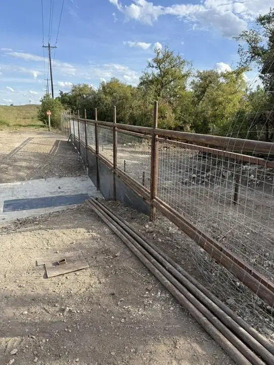 Pipe and wire fence mid-build with pipe stock