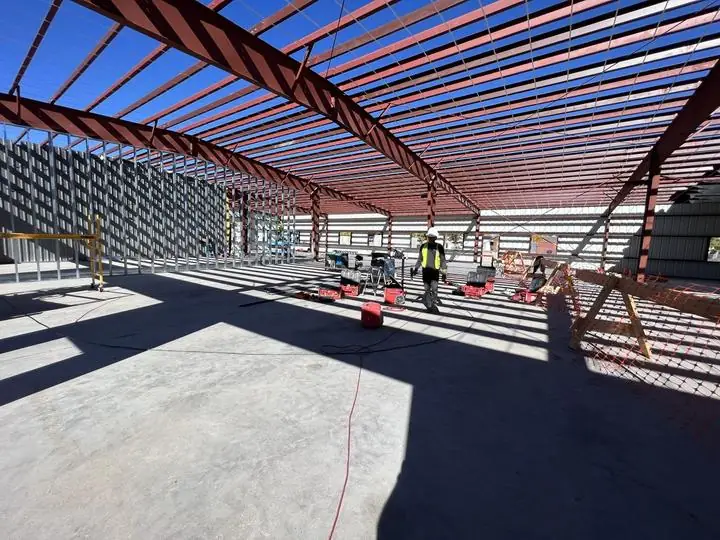 Crew working under a completed red-iron roof frame