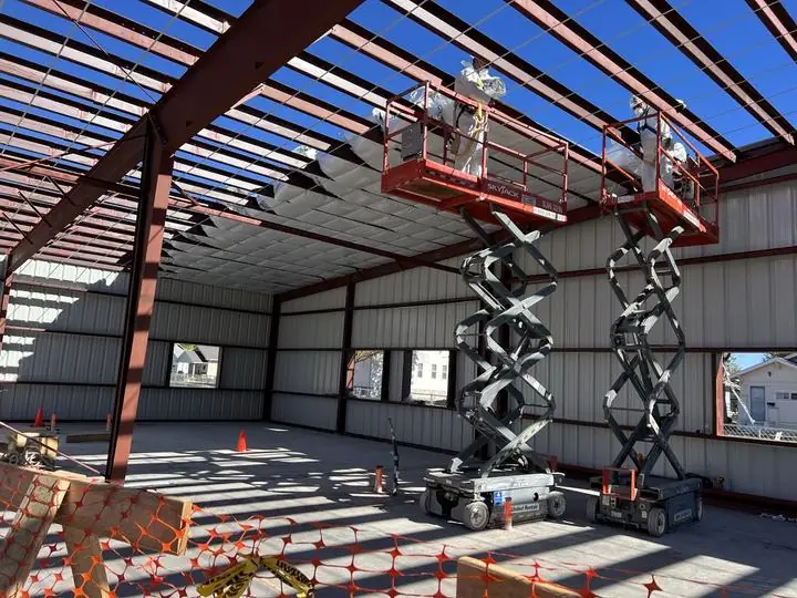Crew on lifts installing roof insulation over red iron